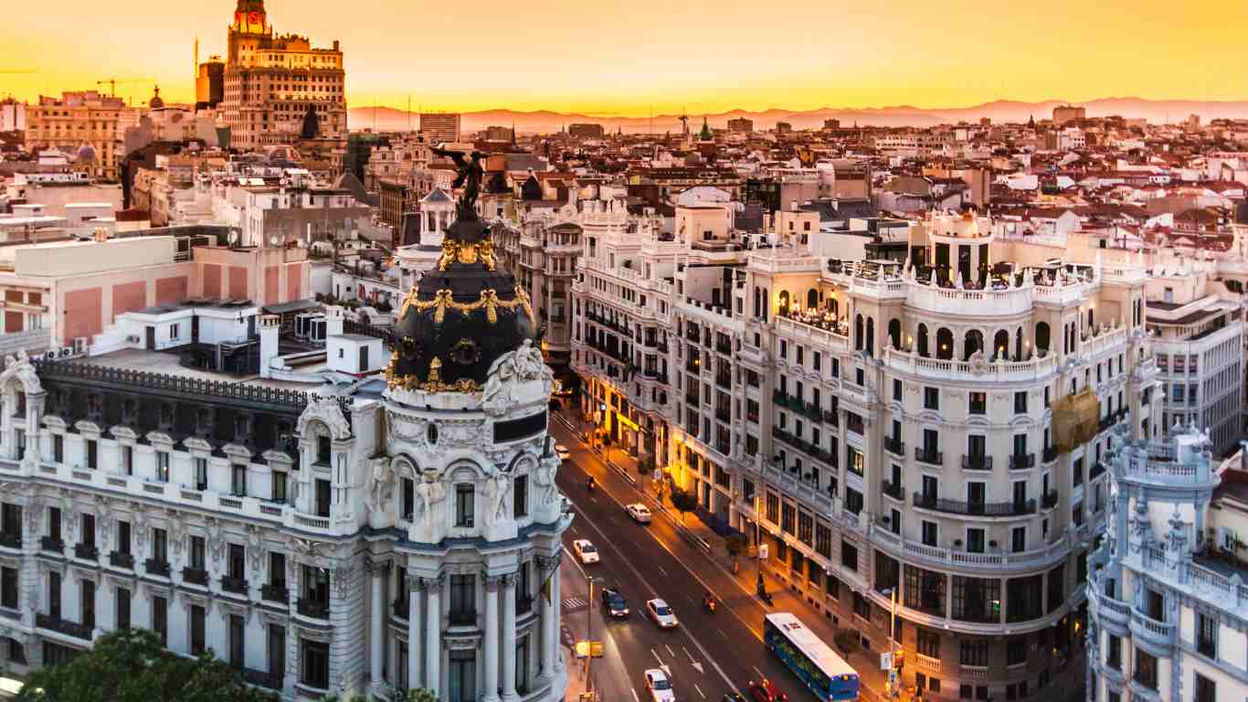 Madrid skyline at sunset with the Metropolis Building and Gran Vía glowing under warm golden light.